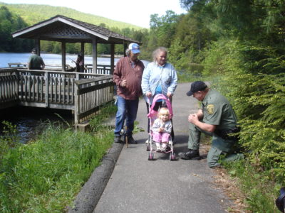 صورة لمسار يمكن الوصول إليه بواسطة الكراسي المتحركة، مع طفل صغير في عربة أطفال وردية اللون على المسار