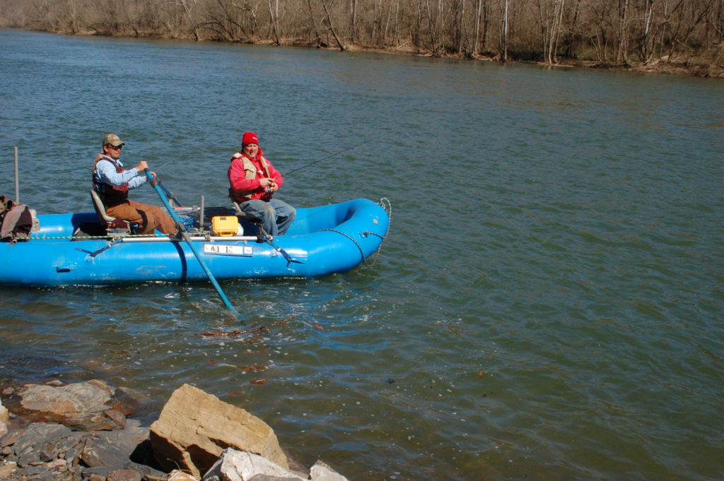 صورة لرجلين على طوافة زرقاء يصطادان السمك بالقرب من بركة صخرية عميقة