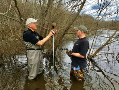 صورة لاثنين من موظفي محطة طاقة البرسيم يضعان صندوق تعشيش على حامل في النهر
