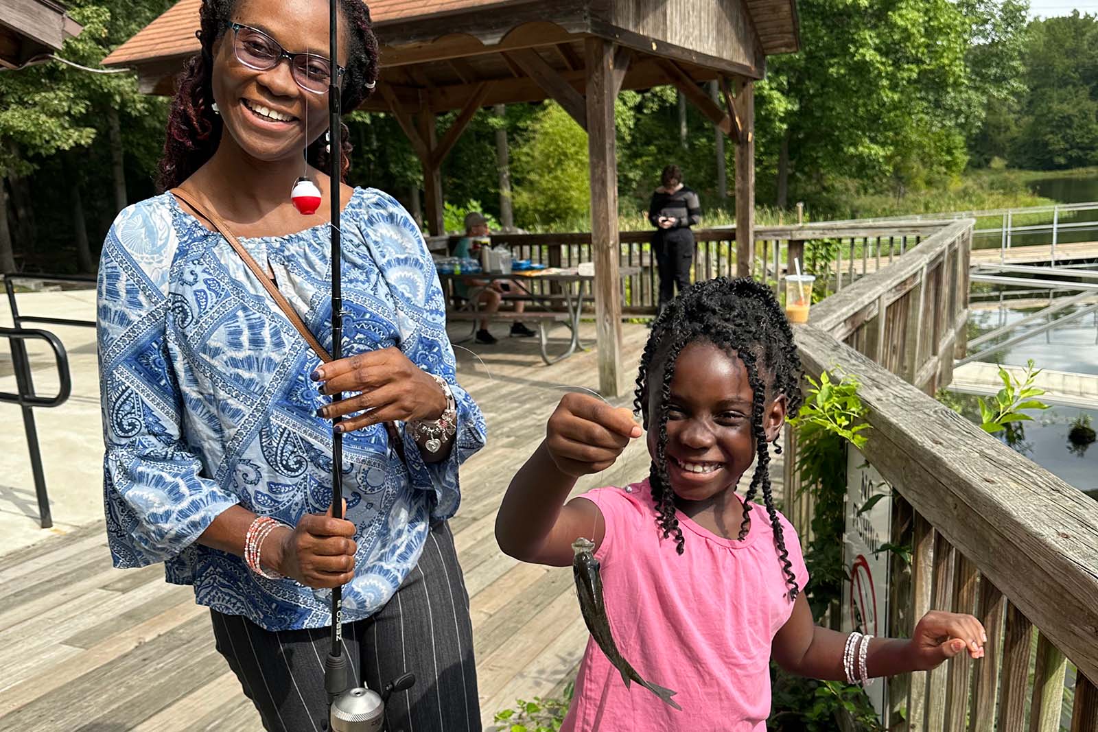 امرأة وطفل يحملان صنارة صيد وسمكة