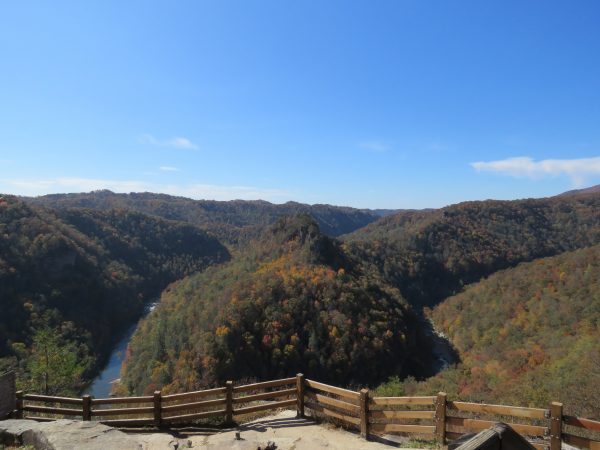 صورة لمطل في منتزه بين الولايات في بريك، وهي صورة لسلسلة جبال خريفية جميلة مع نهر يتدفق في الزاوية اليسرى السفلى وحاجز من الأسوار الخشبية فوق صخرة في المقدمة.