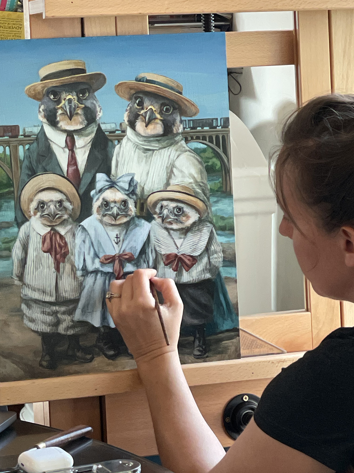 صورة لامرأة ترسم لوحة كبيرة لصقرين بالغين وثلاثة صقور شاهين صغار يرتدون ملابس أمام نهر جيمس في ريتشموند.