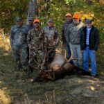 مجموعة من سبعة رجال يقفون مع ظبي مقتول.