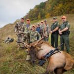 ثمانية رجال يقفون مع ظبي مقتول.