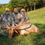 ثلاثة رجال يقفون جاثين على ركبهم مع ظبي نافق.