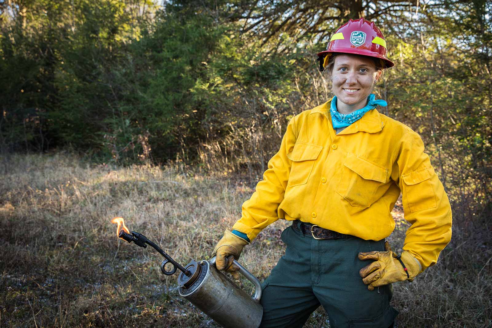 أحد أفراد طاقم الإطفاء يقف حاملاً مصباحاً للتنقيط.