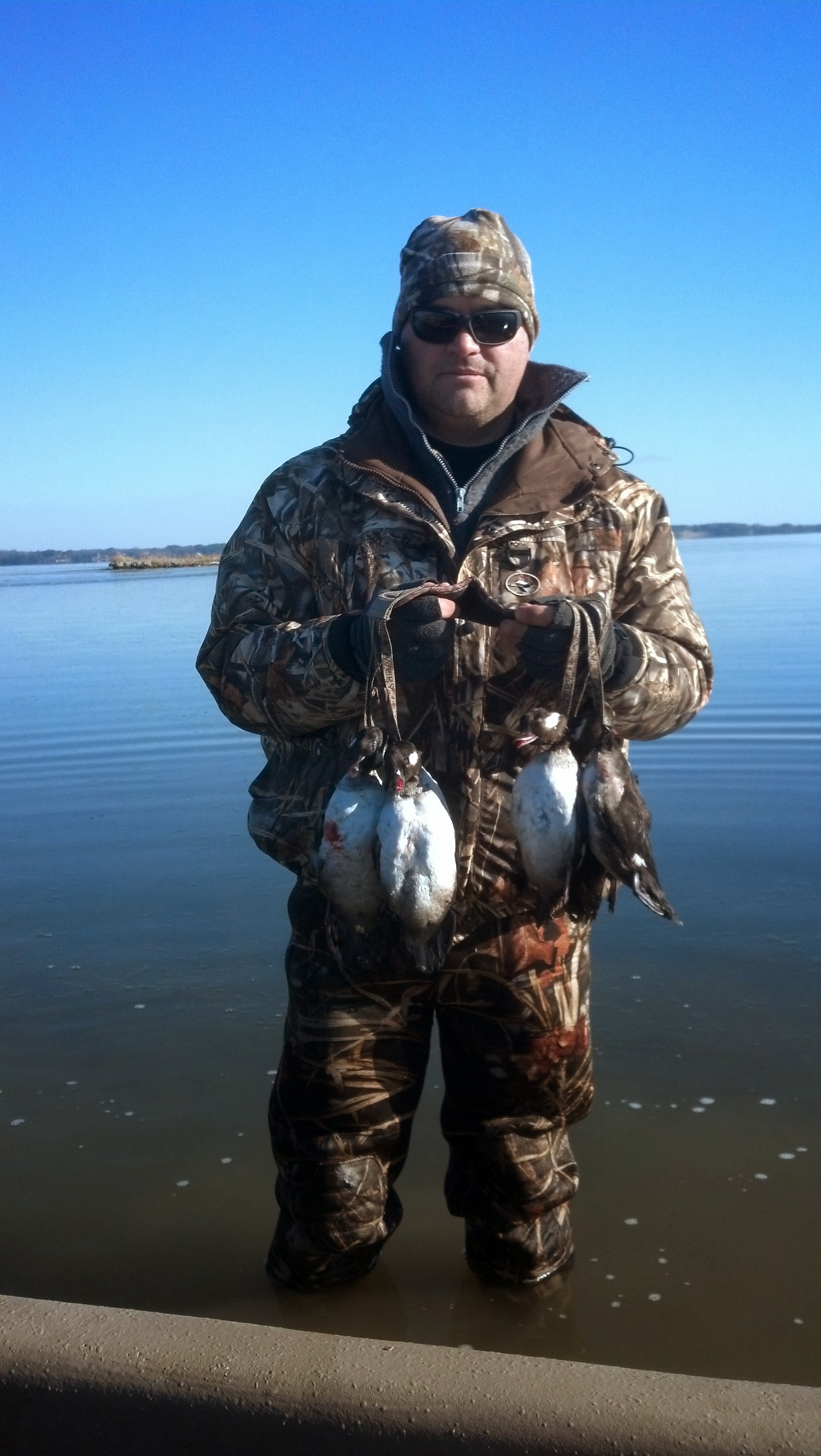 صورة لرجل في ماء مثلج يحمل مجموعة من البط الميت