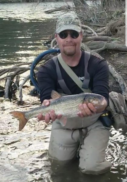 صورة لجيري هول في إحدى الأراضي الرطبة وهو يحمل سمكة الفالش ذات الحجم القياسي في الولاية