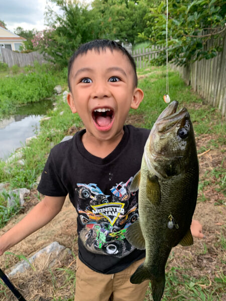 صبي صغير، عمره 5 ، يقف بحماس مع سمكة.