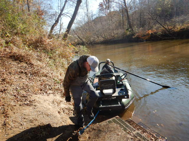 قارب الصيد الكهربائي الأخضر الذي يتم إنزاله من اليابسة مع اثنين من الموظفين