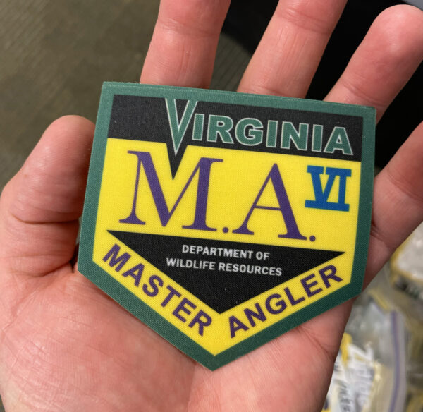 صورة ليد تحمل رقعة قابلة للكي مكتوب عليها "Virginia Master Angler VI".