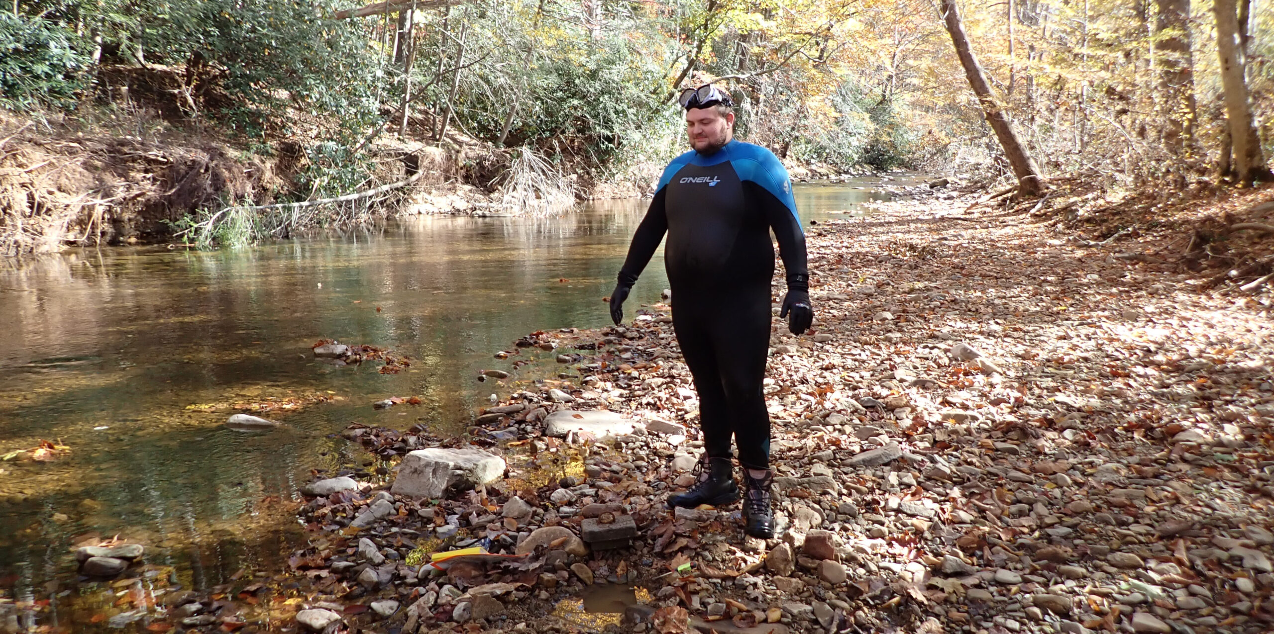 صورة لمجرى مائي مع مساحة كبيرة من الصخور المكشوفة على أحد جانبيه، مع رجل يقف على الصخور مع مربع صغير من الخرسانة عند قدميه.