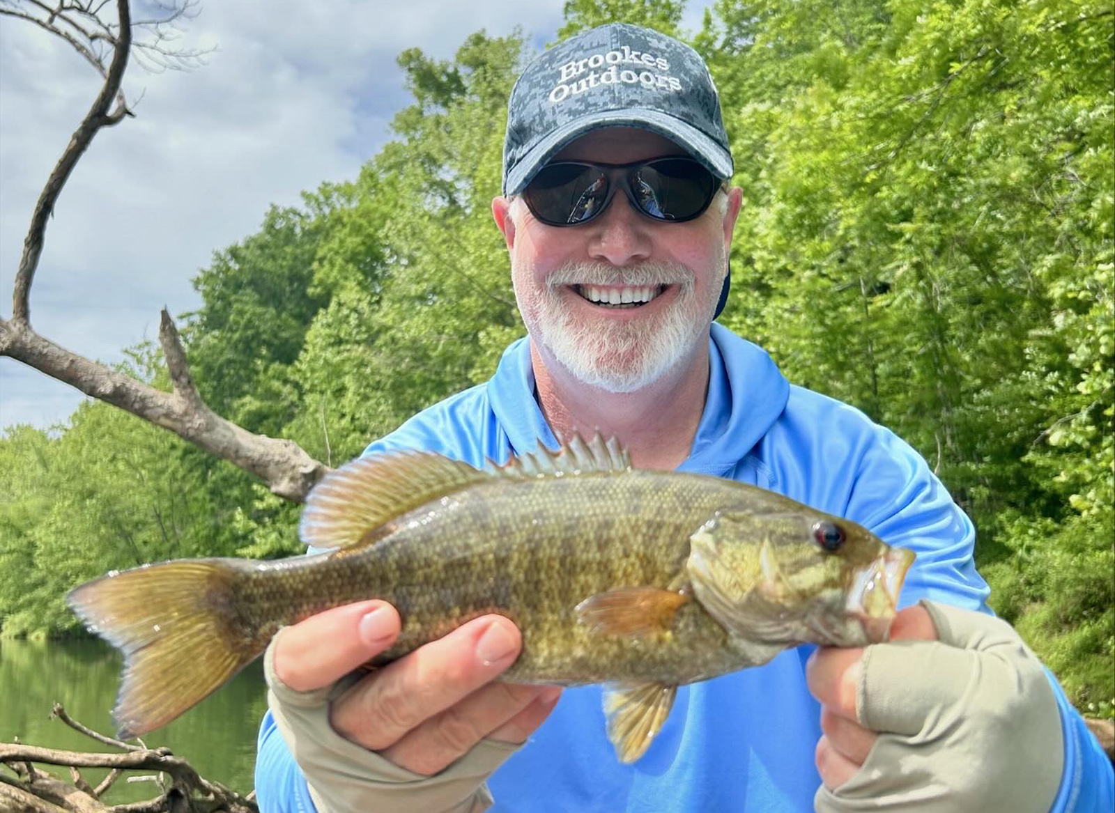 رجل يحمل سمكة سمك القاروس الصغير لالتقاط صورة.