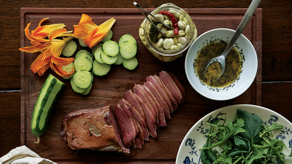 صورة طبق من الأوز المدخن، وزنابق النهار، والخيار، والجرجير، والفاصوليا المخللة