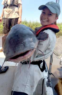 فتاة تحمل سمكة سلور زرقاء كبيرة